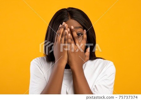 Young black woman covering eyes with palms 75737374