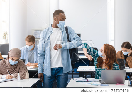Diverse multicultural people wearing face masks greeting and bumping elbows 75737426
