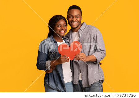 Joyful Loving Black Couple Holding Red Paper Heart Together And Hugging Joyful Loving Black Couple Holding Red Paper Heart Together And Hugging 75737720