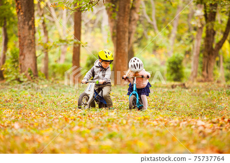 Cheerful preschool kids outdoors on balance bikes 75737764