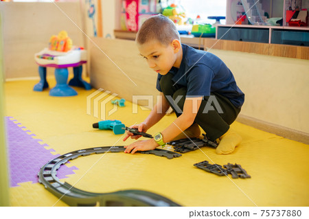 The cute child is playing with toy cars at home 75737880