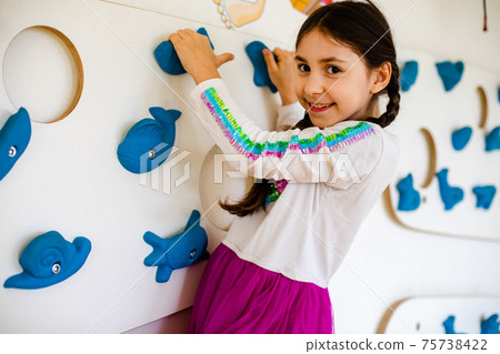 The little girl is climbing on the wall in the playroom 75738422