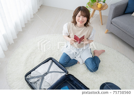 一個年輕女子在客廳裡看著她的護照為旅行做準備 75738560