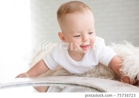 Little boy of 7 months plays on the white carpet in the bedroom 75738723