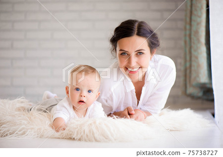 Mom and baby boy in diaper playing in sunny bedroom. Family havi 75738727