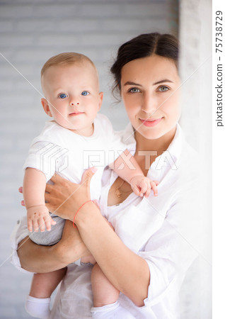 Mother and child in a white room. Mom and baby boy in diaper pla 75738729