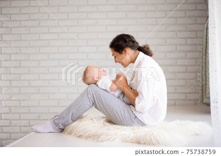 Mom and baby boy in diaper playing in sunny bedroom. Family havi 75738759