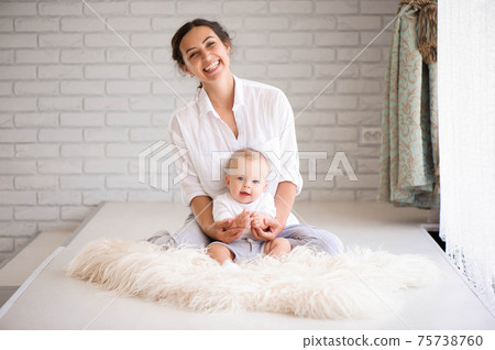 Mom and baby boy in diaper playing in sunny bedroom. Family havi 75738760