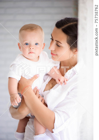 Mother and child in a white room. Mom and baby boy in diaper pla 75738762