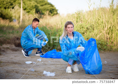 Volunteer man collecting trash on the beach. Ecology concept. Volunteer man collecting trash on the beach. Ecology concept. 75738847