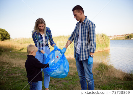 volunteering, charity, people and ecology concept, volunteers using garbage bag while collecting 75738869