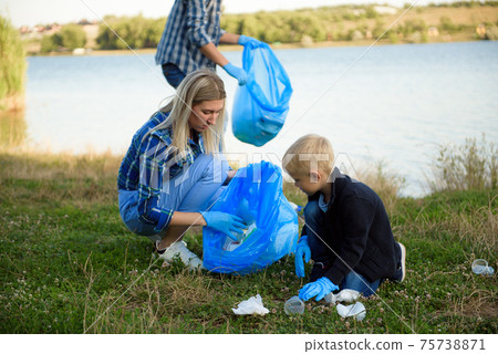 volunteering, charity, people and ecology concept, volunteers using garbage bag while collecting 75738871