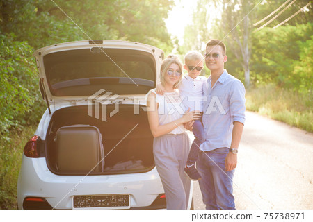 Family, transport, road trip and people concept - happy man and woman with little child travel. 75738971