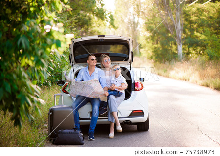 A man a woman and a child of four years in the woods next to the car is ready to travel and choose a A man a woman and a child of four years in the woods next to the car is ready to travel and choose a 75738973