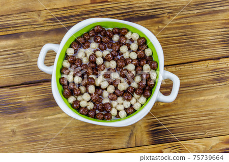 Cereal chocolate balls with milk in a bowl on wooden table. Top view 75739664