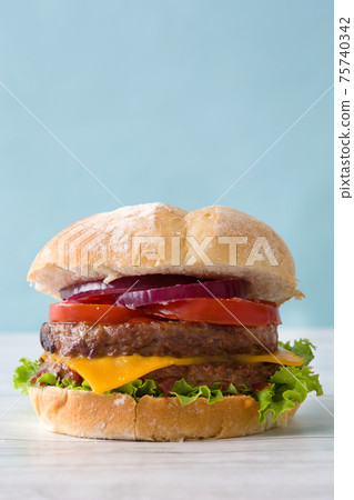 Cheeseburger with beef,tomato, lettuce and onion on wooden table Cheeseburger with beef,tomato, lettuce and onion on wooden table 75740342