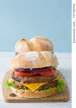 Cheeseburger with beef,tomato, lettuce and onion on wooden table Cheeseburger with beef,tomato, lettuce and onion on wooden table 75740344