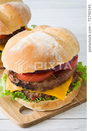 Cheeseburger with beef,tomato, lettuce and onion on wooden table Cheeseburger with beef,tomato, lettuce and onion on wooden table 75740345