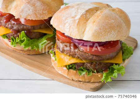 Cheeseburger with beef,tomato, lettuce and onion on wooden table Cheeseburger with beef,tomato, lettuce and onion on wooden table 75740346