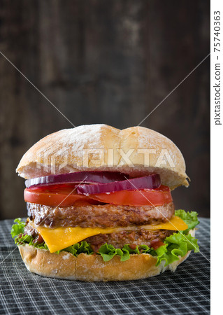 Cheeseburger with beef,tomato, lettuce and onion on wooden table Cheeseburger with beef,tomato, lettuce and onion on wooden table 75740363