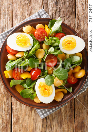 Fresh salad of lupine beans, eggs, tomatoes and Valerianella locusta close-up in a plate. vertical top view 75742447