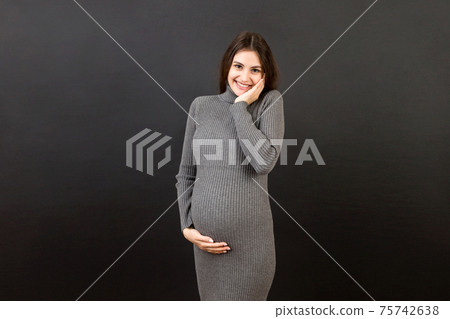Happy pregnant woman touching her abdomen at Colored background. Future mother is wearing white underwear. Expecting of a baby. Copy space Happy pregnant woman touching her abdomen at Colored background. Future mother is wearing white underwear. Expecting of a baby. Copy space 75742638