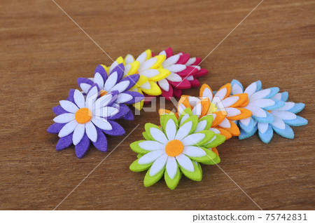 Images of flowers made of colourful felt fabrics. Isolated on wood grain texture background. Images of flowers made of colourful felt fabrics. Isolated on wood grain texture background. 75742831