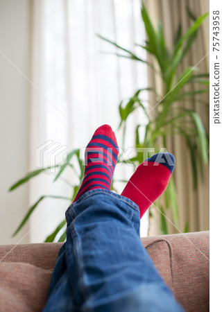 Crossed legs in red socks resting on sofa. Close up. Crossed legs in red socks resting on sofa. Close up. 75743958