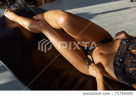 Sexy woman in lingerie posing on leather sofa 75744000