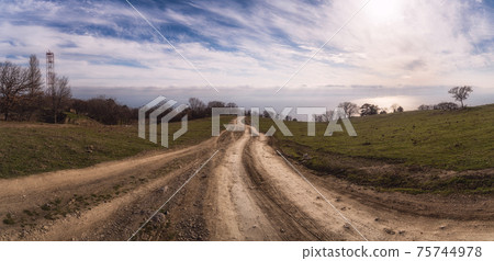 A gravel road leading toward horizon. Spectacular view on the sea and blue sky in the evening. Panoramic image A gravel road leading toward horizon. Spectacular view on the sea and blue sky in the evening. Panoramic image 75744978