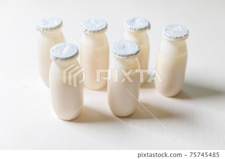 Small bottles with probiotics and prebiotics dairy drink on white background. Production with biologically active additives. Fermentation and diet healthy food. Bio yogurt with useful microorganisms. 75745485