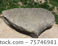 Encoded ancient engraved inscription by Gothic font with missing letters on a large boulder 75746981