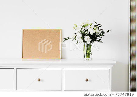 Golden horizontal frame and bouquet of fresh flowers on white furniture, luxury home decor and design for mockup creation 75747919