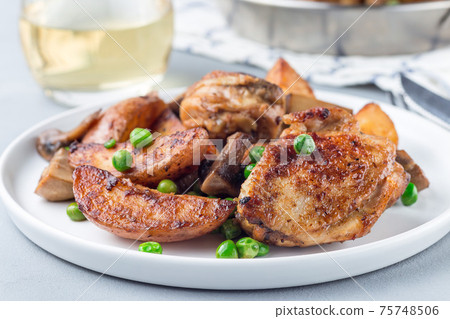 Chicken with potatoes, mushrooms and green peas, on a white plate and in metal pot, horizontal Chicken with potatoes, mushrooms and green peas, on a white plate and in metal pot, horizontal 75748506