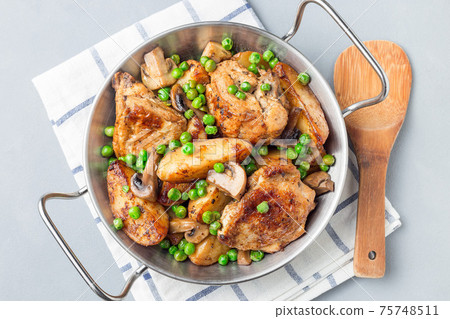 Chicken with potatoes, mushrooms and green peas, in metal pot, horizontal, top view, closeup 75748511