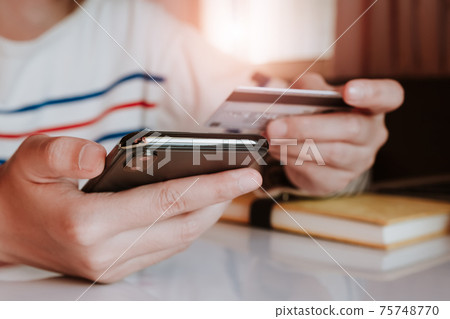 Online payment, Woman's hands holding a credit card and using smart phone  75748770