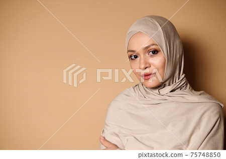 Confident portrait of a serene and beautiful Arab Muslim woman in hijab and strict conservative attire 75748850