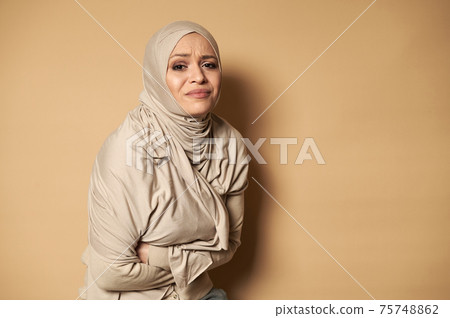 Woman woman wearing hijab having stomach ache. Young woman suffering from abdominal pain Woman woman wearing hijab having stomach ache. Young woman suffering from abdominal pain 75748862
