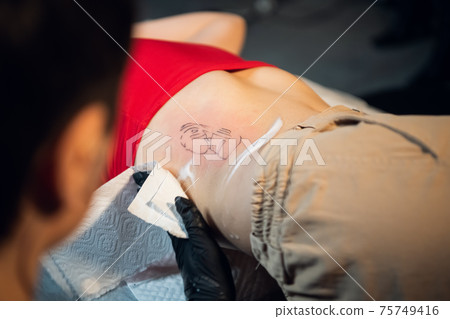 Filling the tattoo is finished, the master treats the skin with a wound-healing foam 75749416