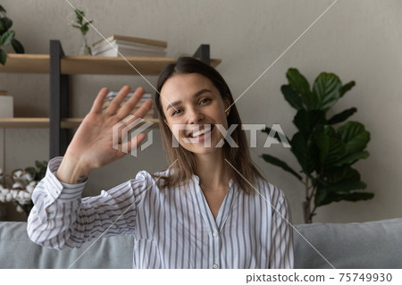 Head shot portrait smiling woman waving hand at camera Head shot portrait smiling woman waving hand at camera 75749930