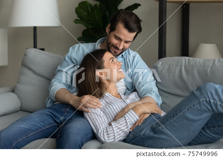 Close up happy young couple relaxing on couch together Close up happy young couple relaxing on couch together 75749996