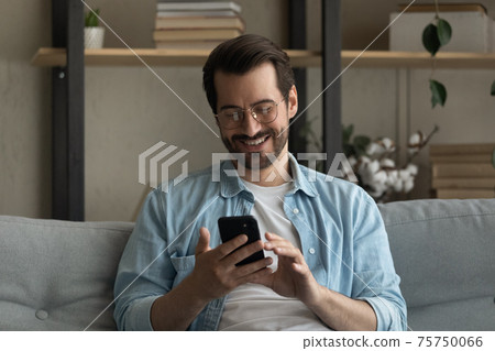 Close up smiling man wearing glasses using smartphone at home Close up smiling man wearing glasses using smartphone at home 75750066