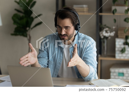 Close up confident man wearing headphones using laptop, internet meeting 75750092