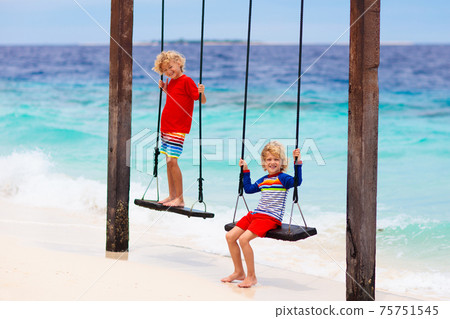 Child on beach swing. Summer vacation. Child on beach swing. Summer vacation. 75751545