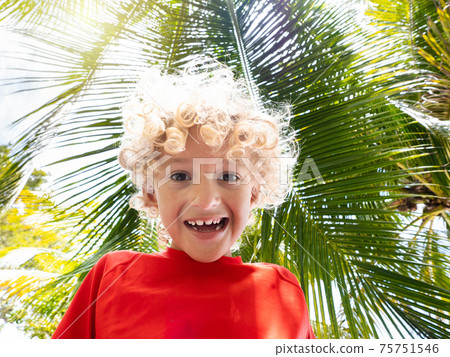 Beach fun. Curly boy under palm tree. 75751546
