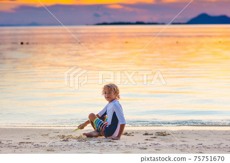 Child playing on ocean beach. Kid at sunset sea. Child playing on ocean beach. Kid at sunset sea. 75751670