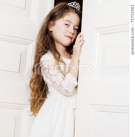 little cute girl at home, opening door well-dressed in white dress, adorable milk fairy teeth 75752001