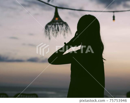 Silhouette of a woman floating in the sunset Silhouette of a woman floating in the sunset 75753946