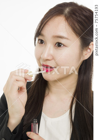 A woman applying lip gloss 75754193