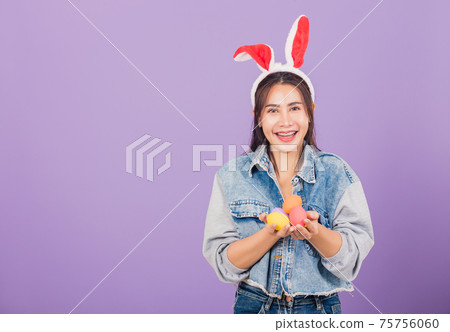 woman smiling wearing rabbit ears and denims hold colorful Easter eggs gift on hands woman smiling wearing rabbit ears and denims hold colorful Easter eggs gift on hands 75756060